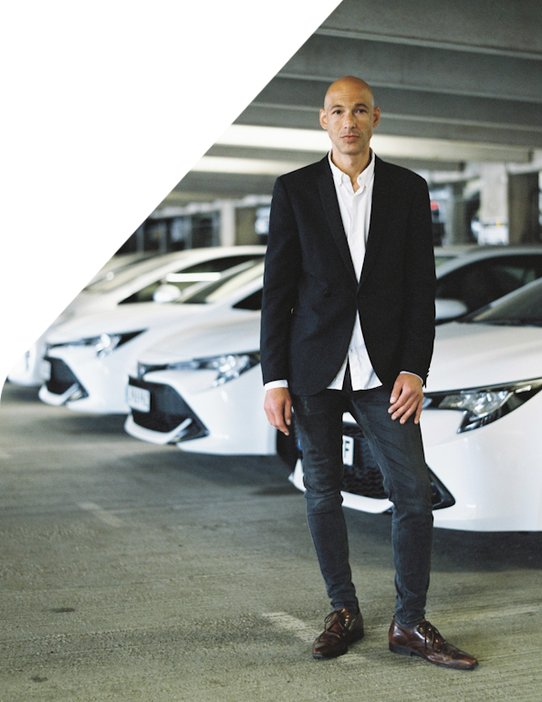 Well-dressed man standing in front of a fleet of sedan cars